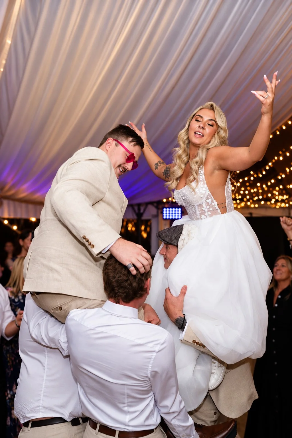 Bride celebrating while lifted by her guests on the dance floor
