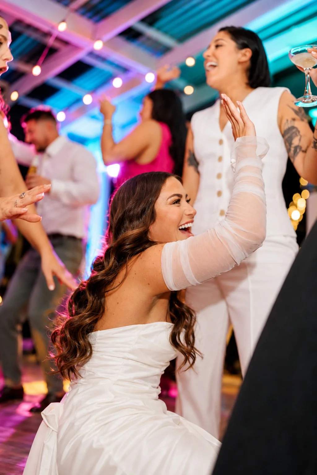 Joyful wedding guests celebrating under colourful reception lights