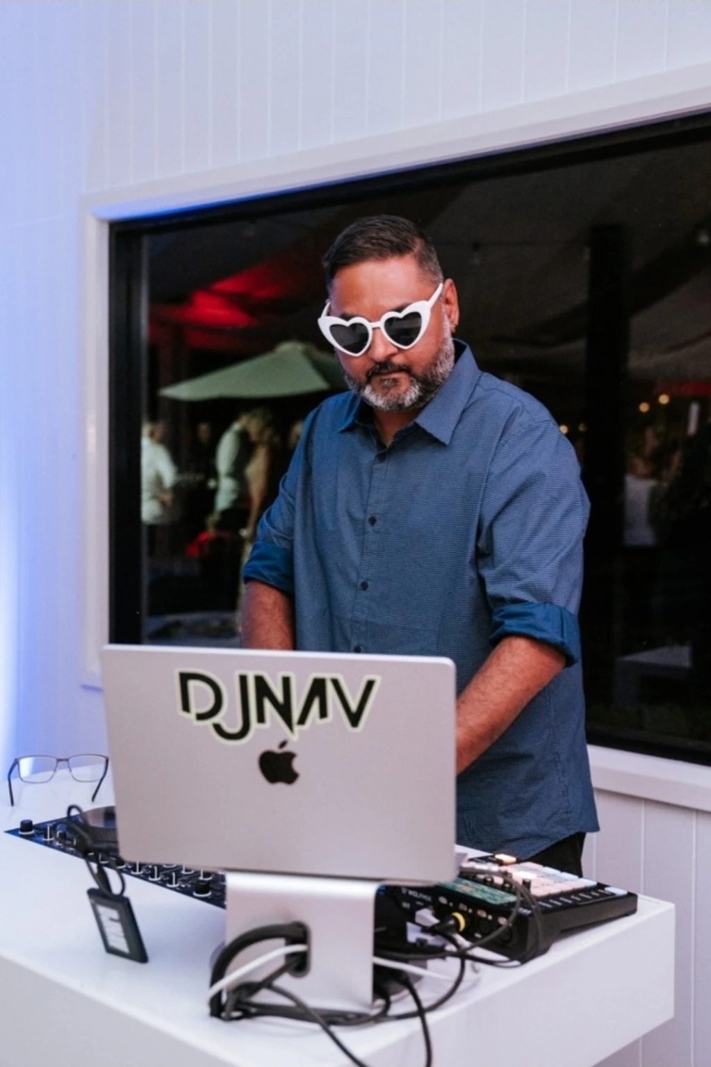 Real photograph of DJNav at a wedding DJ setup wearing heart-shaped glasses