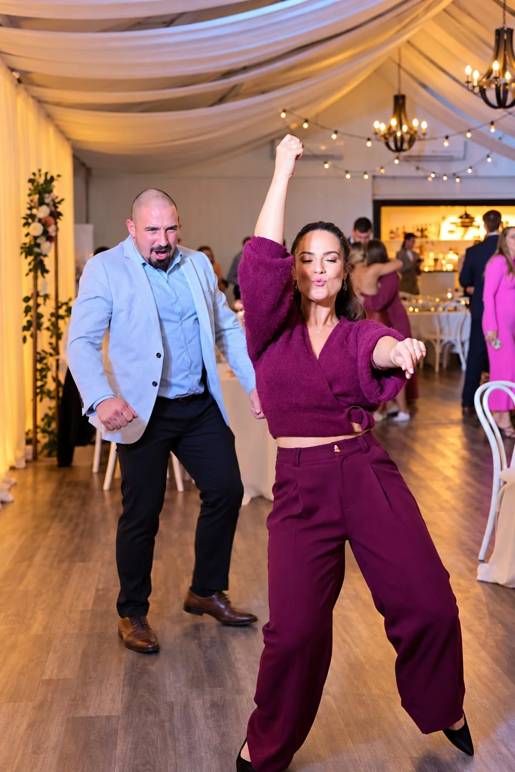Two wedding guests enthusiastically dancing at a reception