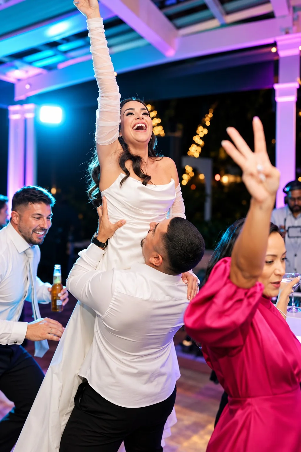 Wedding guests lifting the bride during a lively dance floor celebration