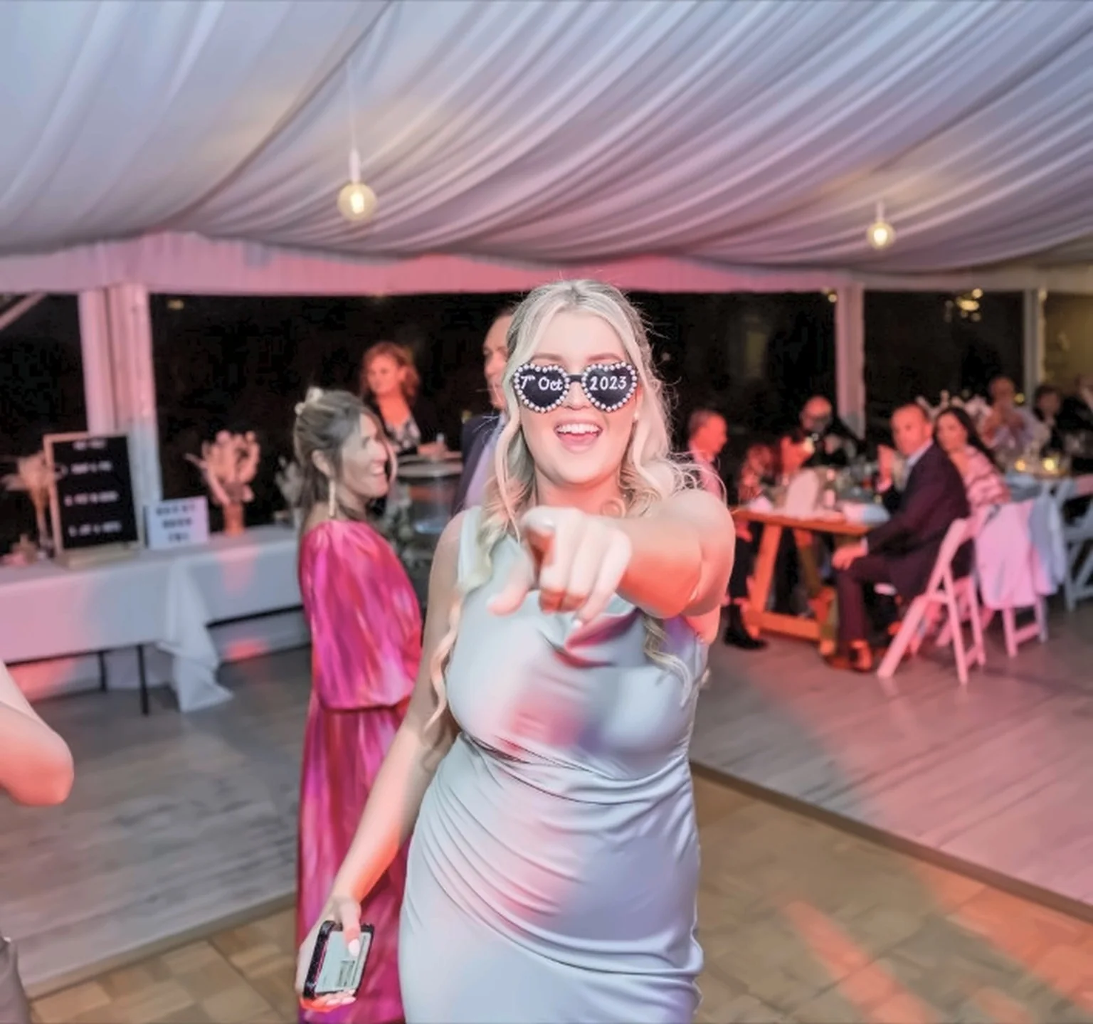 Wedding guest wearing novelty sunglasses dancing and pointing to camera