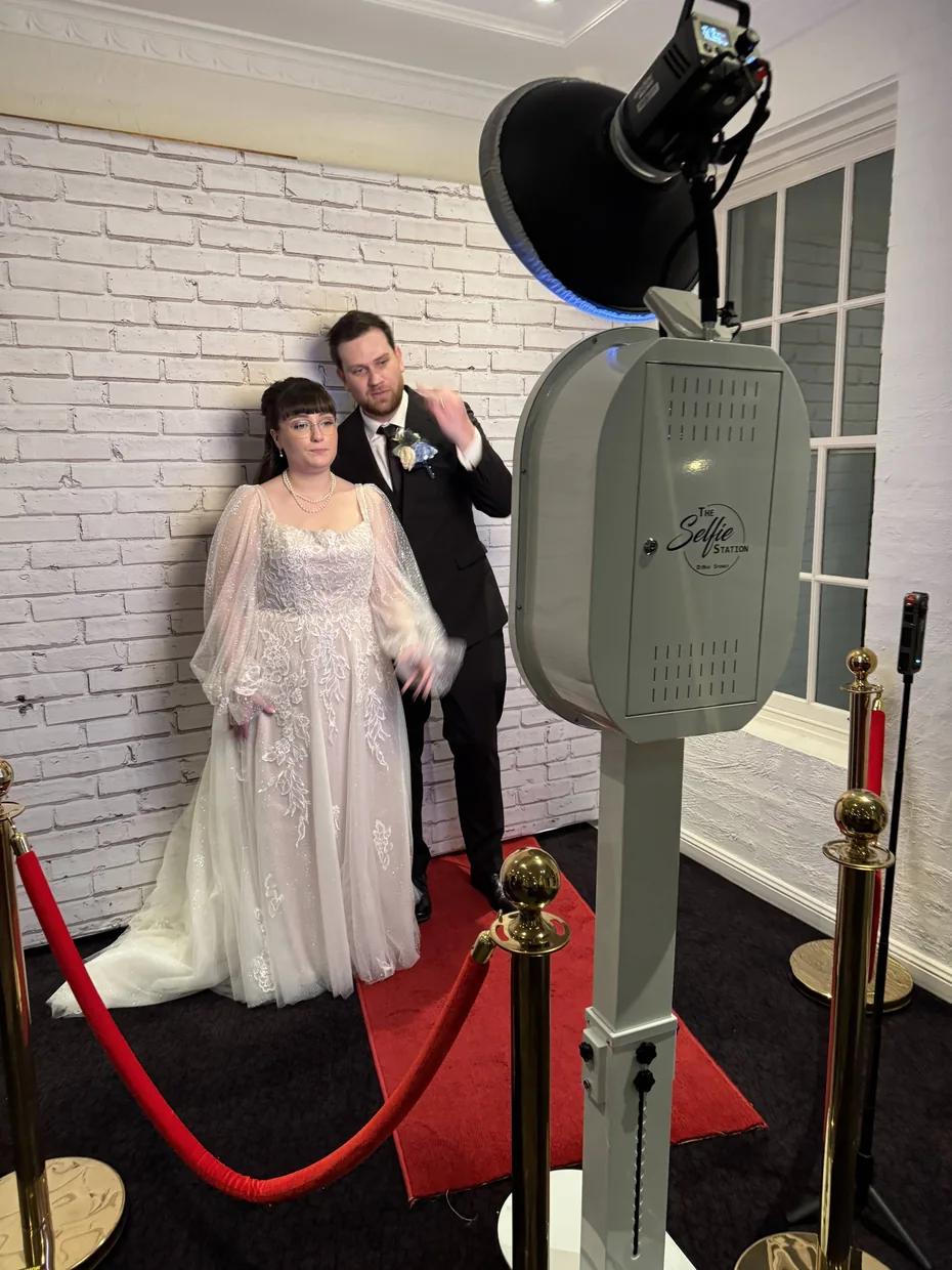 Guest posing beside The Selfie Station at a wedding